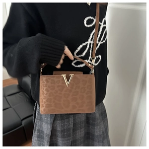Close-up of leopard print handbag featuring a gold V logo and textured animal fur finish