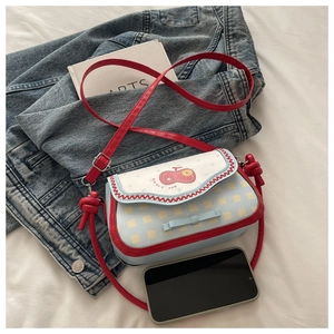 Détail du sac à carreaux avec imprimé cerise, nœud bleu et bandoulière rouge nouée