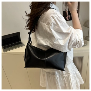Detail view of black minimalist underarm bag with unique knotted strap on shoulder