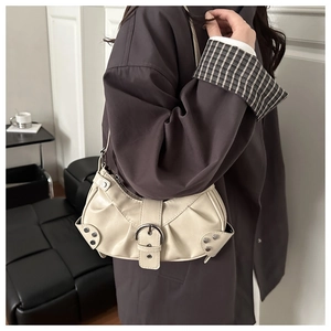 Close-up of beige pleated underarm bag featuring silver rivets and retro buckle details