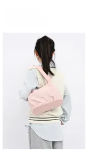 Detailed view of pink textured nylon shoulder bag with wide strap on a model