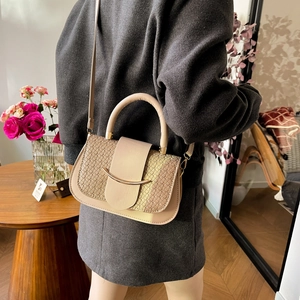 Elegante beige zadeltas met geweven textuur en gouden gesp gedragen door model