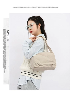 Detailed texture of khaki pleated nylon bucket bag worn with a casual vest and shirt
