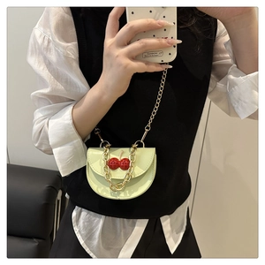 Detail of pistachio green mini crossbody bag with red cherry charm and gold chain strap
