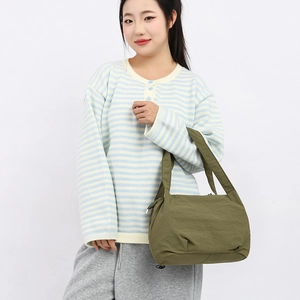 Minimalist olive green bucket bag shown as a versatile shoulder bag on a model