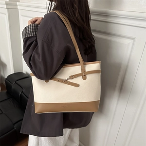 Minimalist large capacity tote bag in cream and brown textured leather shown on shoulder
