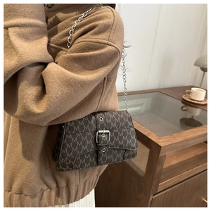 Détail du sac marron foncé avec motif de lettres M et bandoulière chaîne argent