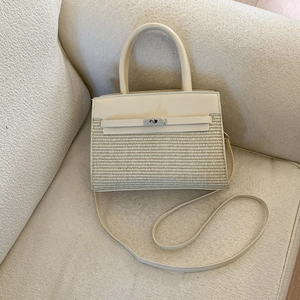 Detail of a beige patchwork handbag with textured weaving and silver metal clasp lock