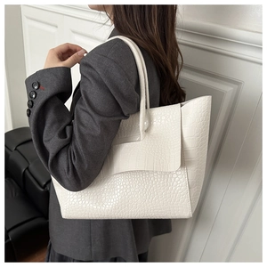 Detail of a large crocodile-embossed white tote bag on a model side view for office style