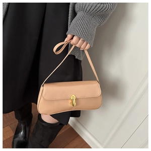 Detail of beige baguette bag with golden oval buckle and smooth finish on the shoulder strap