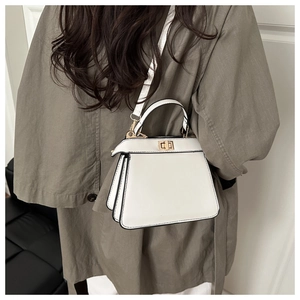 Détail d'un sac à bandoulière en cuir blanc avec finitions dorées et fermoir pivotant chic