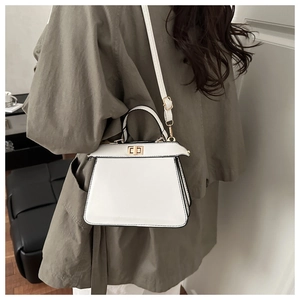 Détail d'un sac à main trapèze blanc avec fermoir doré et bords peints en noir