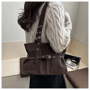 Detail of dark brown leather tote bag with metallic eyelets and adjustable buckle straps