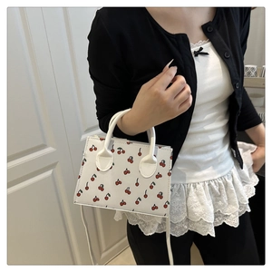Detail shot of cherry print mini square bag featuring premium white faux leather finish