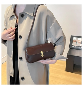 Brown faux leather shoulder bag with vintage gold metal buckle worn with a beige coat