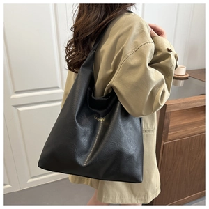 Detail view of large black oil wax leather tote bag with minimalist FASHION gold lettering