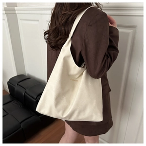 Detail of a large cream tote bag with textured faux leather and golden FASHION text