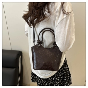 Close-up of dark brown embossed bucket bag with glossy heart and love song patterns