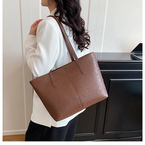 Detailed texture of dark brown crocodile-embossed leather on a spacious tote bag