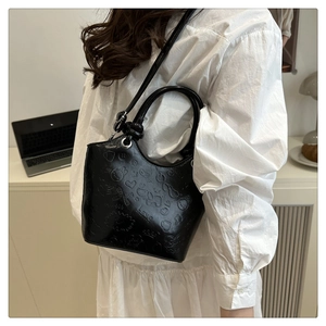 Detail of black embossed bucket bag featuring cartoon patterns and heart shapes