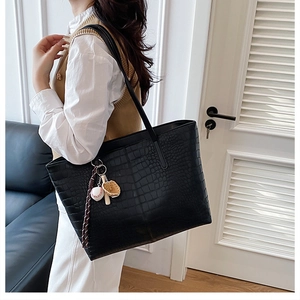 Side view of black faux-crocodile leather tote bag featuring a baseball glove charm