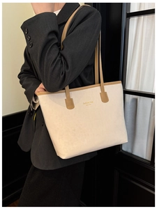 Detail of off-white suede tote bag with brown straps and New York logo on a model