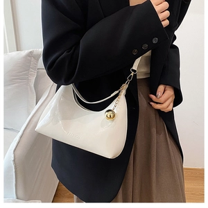 Detail of white patent leather crescent hobo bag with gold sphere charm and fashion logo