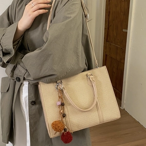 Sac cabas tissé kaki avec bandoulière cuir et pendentif décoratif sur manteau vert