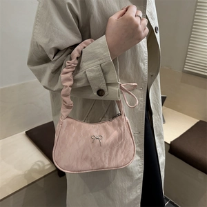 Pink pleated underarm bag with silver metallic bow and ruffled shoulder strap on model