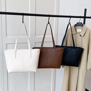 Minimalist crocodile pattern tote bags in cream, brown, and black hanging for storage