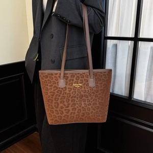 Chic brown leopard print tote bag with leather strap shown on grey suit model