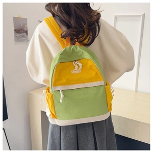 Detail of green and yellow nylon backpack with adjustable straps and front zip pocket