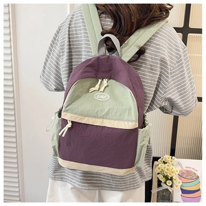 Detail view of contrast purple and sage green nylon backpack with drawstring side pocket
