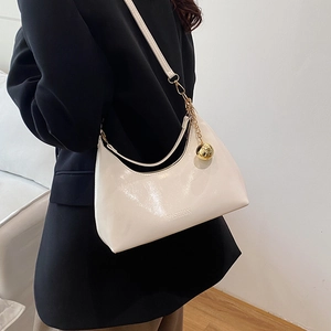 Chic cream-colored glossy hobo shoulder bag with gold chain and spherical charm