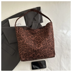 Leopard print tote bag styled over a dark blazer with modern lifestyle accessories