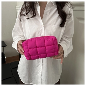 Detail of rose pink quilted puffer clutch bag with soft texture held by a model