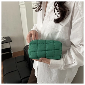 Detail of green quilted puffer cosmetic bag with checkerboard pattern and metal zipper