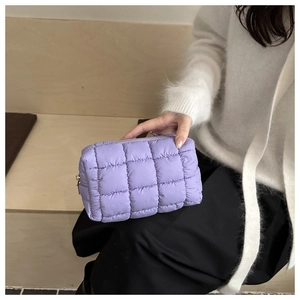 Detail of soft purple quilted down fabric clutch bag held by model for lifestyle view