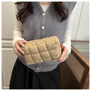 Close-up of khaki quilted down clutch bag with puffy lattice texture and metal zipper