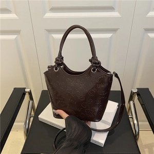 Dark brown embossed tote bag with cartoon patterns and adjustable strap on a chair