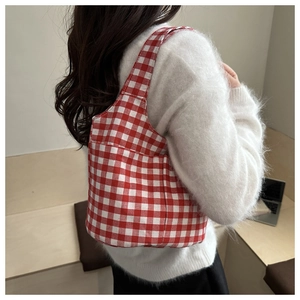 Détail du sac cabas en toile à carreaux vichy rouge et blanc porté par un mannequin