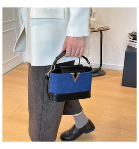 Close-up of quilted color-block handbag featuring a gold V-shaped metal buckle detail