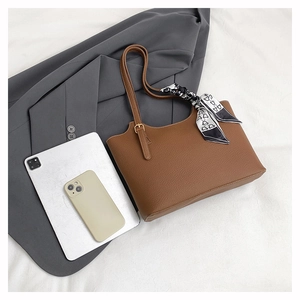 Detailed texture of brown pebble leather tote bag with elegant silk scarf on handle