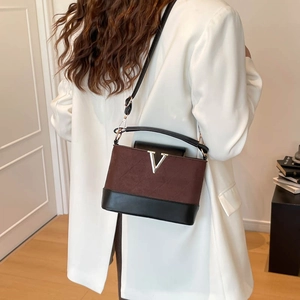 Sac à main matelassé en V en daim marron et cuir noir, porté sur un costume blanc