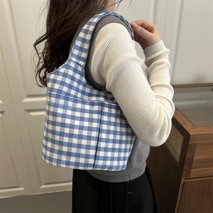 Sac fourre-tout en toile à carreaux bleus et blancs porté à l'épaule avec poches
