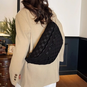 Black checkerboard crossbody chest bag in minimalist style worn by model in vintage room