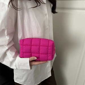 Magenta quilted nylon clutch bag with checkered design held by hand in casual style
