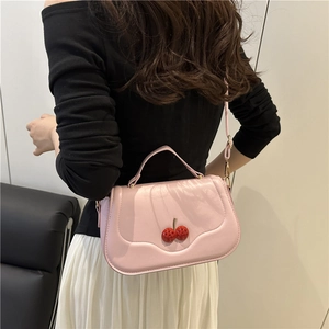 Pink crossbody bag with cherry detail shown on shoulder for casual 2025 winter style