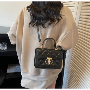 Chic black quilted handbag with gold T-lock shown on a model for scale and style