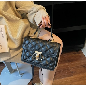 Detail of black quilted shoulder bag with gold clasp and elegant stitch pattern